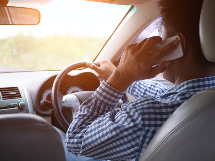 Een man aan de telefoon tijdens het rijden.