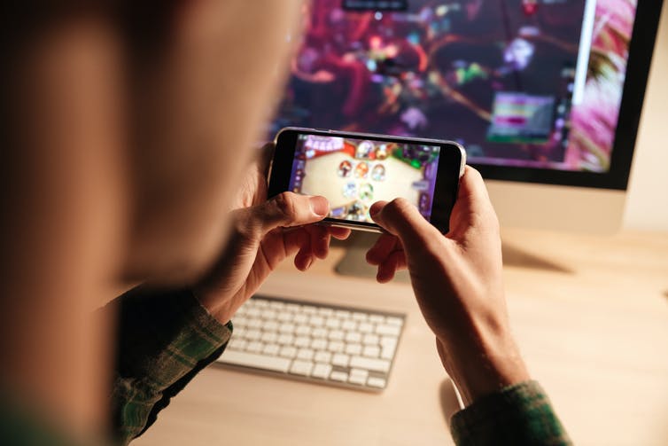 Handen die een spel spelen op een smartphone.