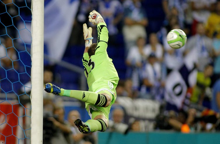 Een keeper springt door de lucht om een ​​voetbal te blokkeren.