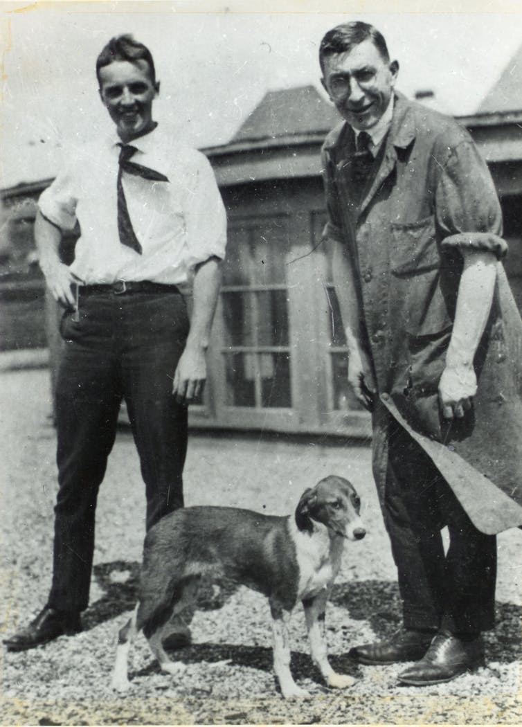 Twee mannen poseren met een hond.
