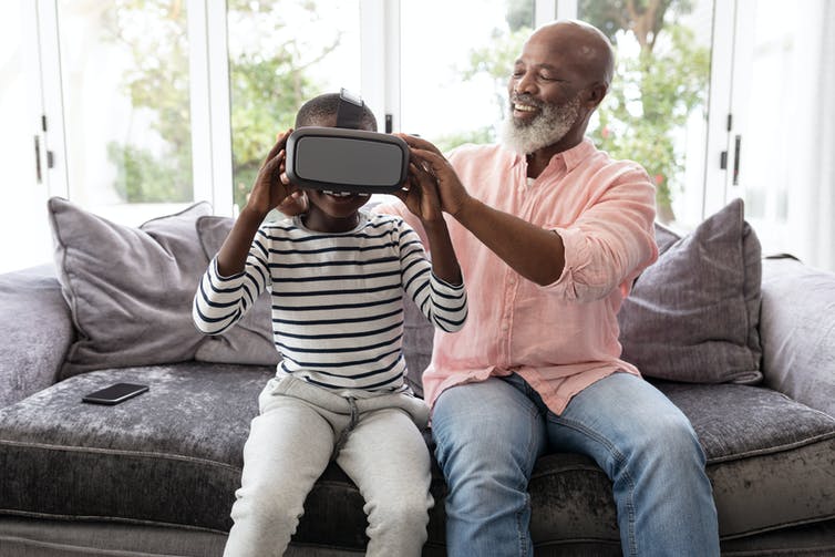 Een man helpt een kind om een VR-headset op te zetten.