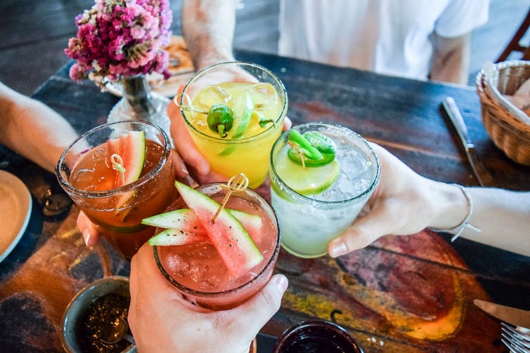 Vier verschillende cocktails van verschillende kleuren.