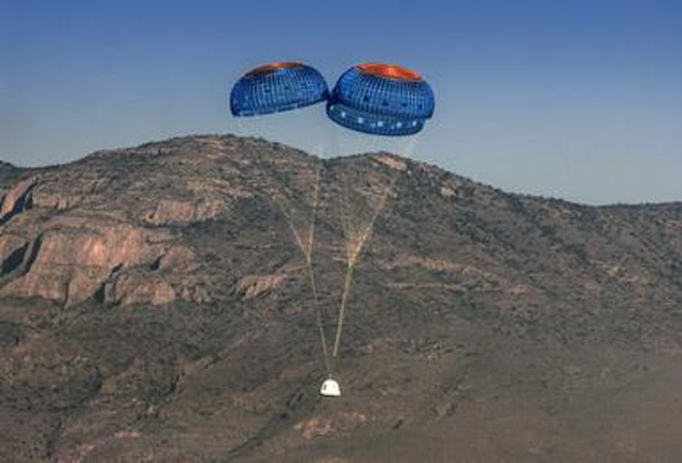 Afbeelding van Blue Origin's New Shepherd ruimteschip dat landt met parachutes.