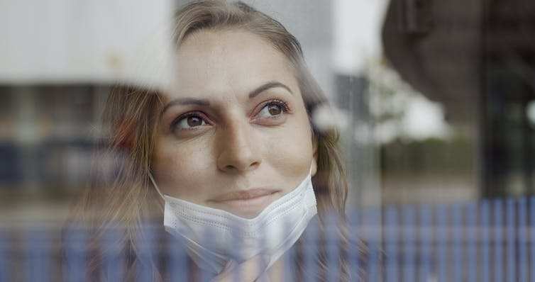 Vrouw met een gezichtsmasker dat haar kaak gedeeltelijk bedekt met een positieve uitdrukking