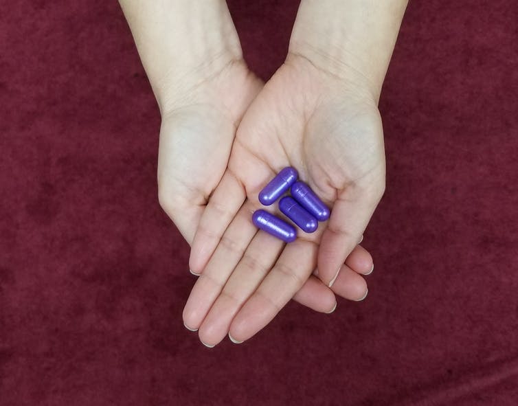 Grote paarse pillen die in de palm van een hand worden gehouden