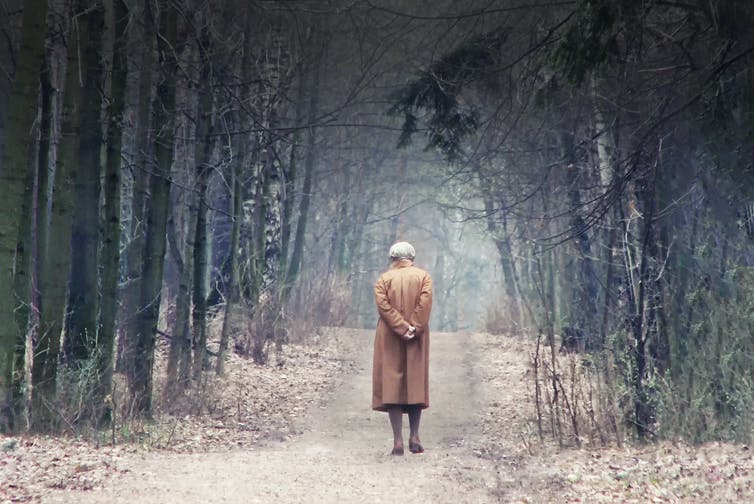 Oude dame loopt alleen in het bos.