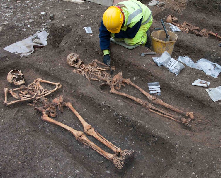 Een archeoloog die de skeletten opgraaft