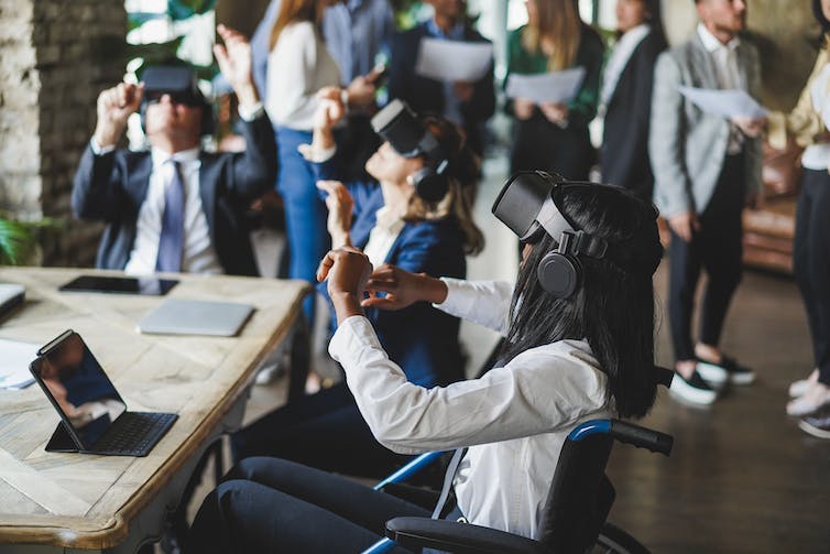 Een groep professionals in een kantoor die VR-headsets dragen en interageren in de metaverse, de focus ligt op een jonge vrouw in een rolstoel