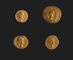 Vier gouden munten van verschillende grootte met verschillende profielen van Romeinse leiders.