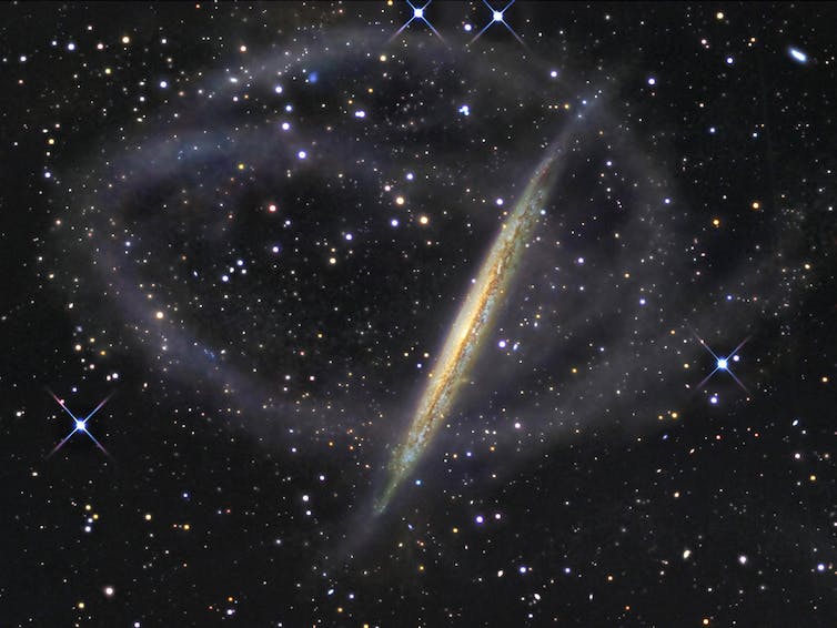 Beeld van NGC 5907, een sterrenstelsel met zwakke stromen van sterren die zich overal omheen wikkelen.