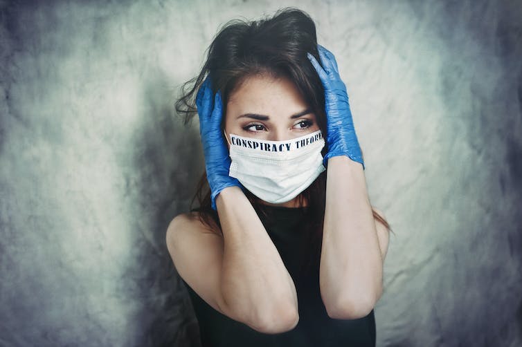 Angstige jonge vrouw in een medisch masker en beschermende chirurgische steriele handschoenen