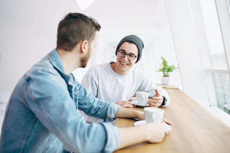 Twee mannen zitten aan een tafel koffie te drinken en te praten