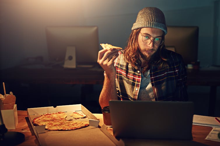 Een pizza eten voor een scherm.